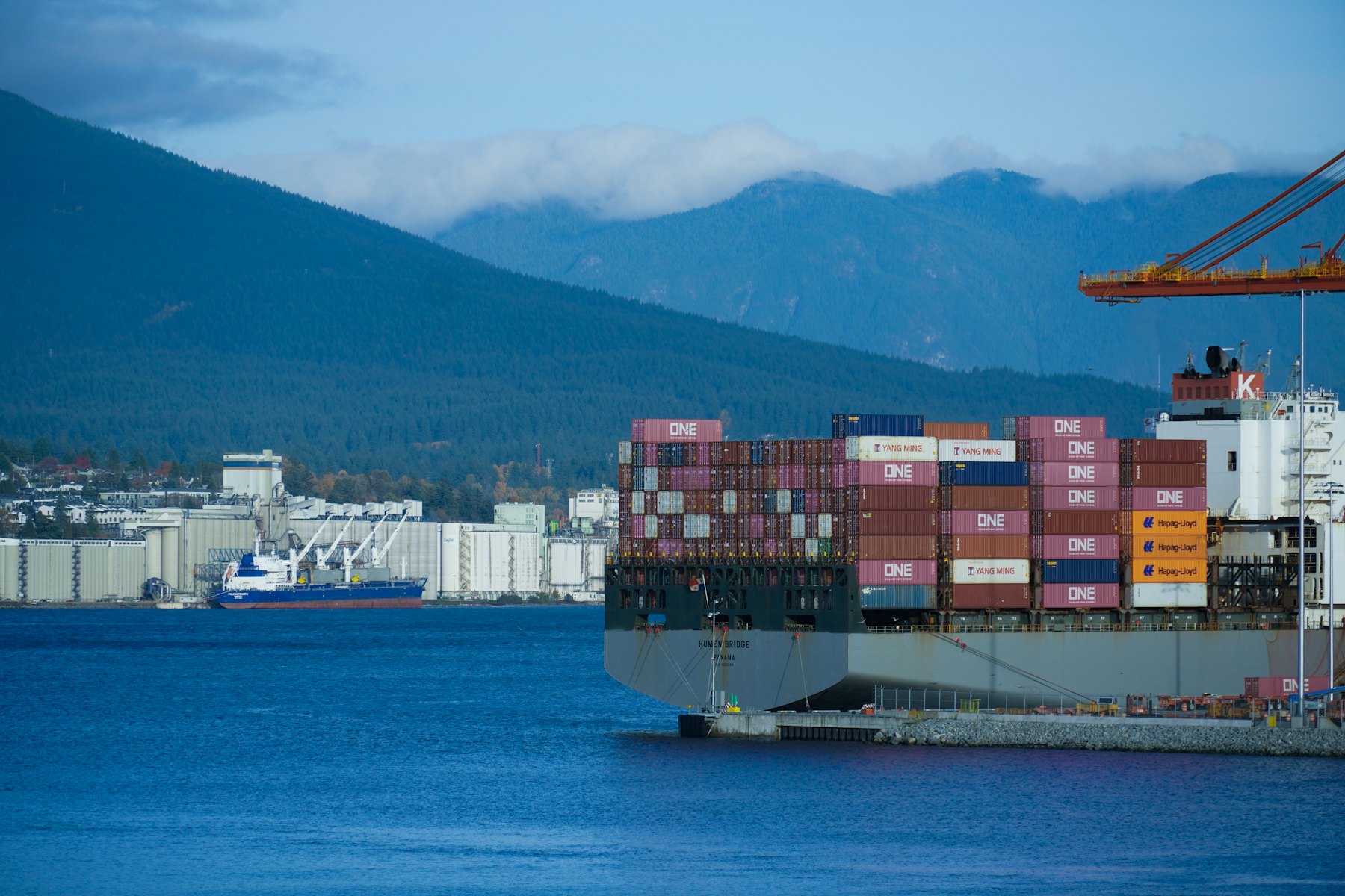 A container ship arriving at a port with mountains behind